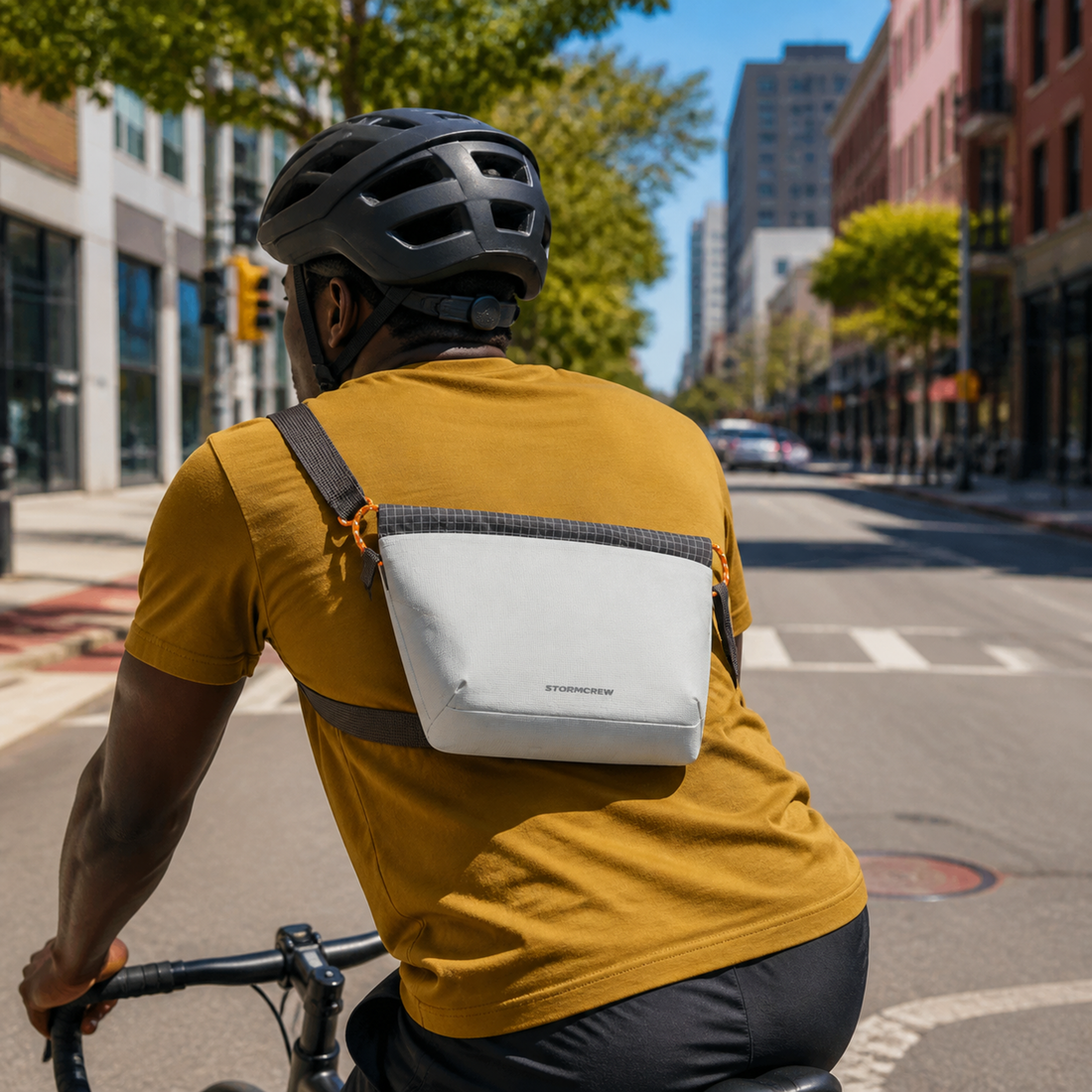 A cyclist riding down an urban street, demonstrating sling bag stability with a secure crossbody strap.