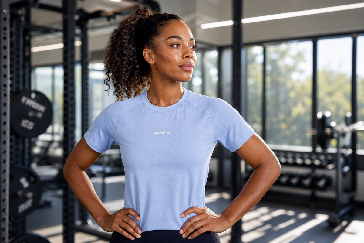 Woman wearing a light blue StormCrew shirt in a gym setting, showcasing high-performance antibacterial t-shirts.
