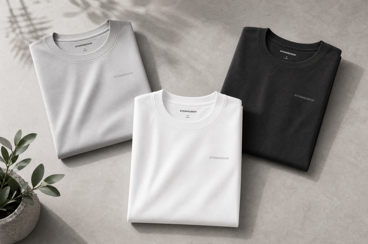 A modern minimalist flat lay of premium athletic training t-shirts in neutral tones, neatly folded on a clean concrete